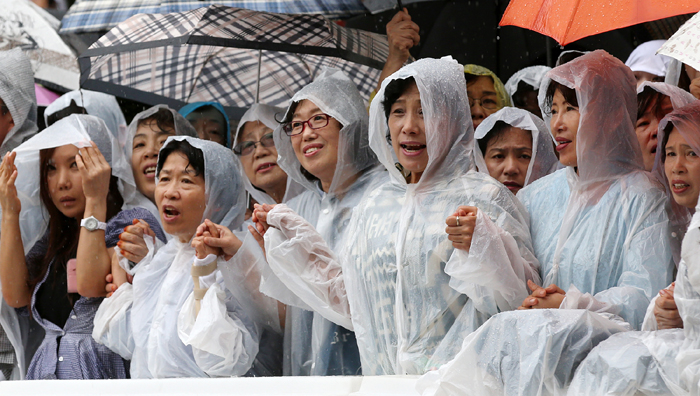  프란치스코 교황이 18일 명동성당에서 ‘평화와 화해를 위한 미사’ 집전하고 있는 가운데 명동성당 앞에 몰려든 신도들이 비가 오는 가운데서도 자리를 떠나지 않고 기도를 드리고 있다.