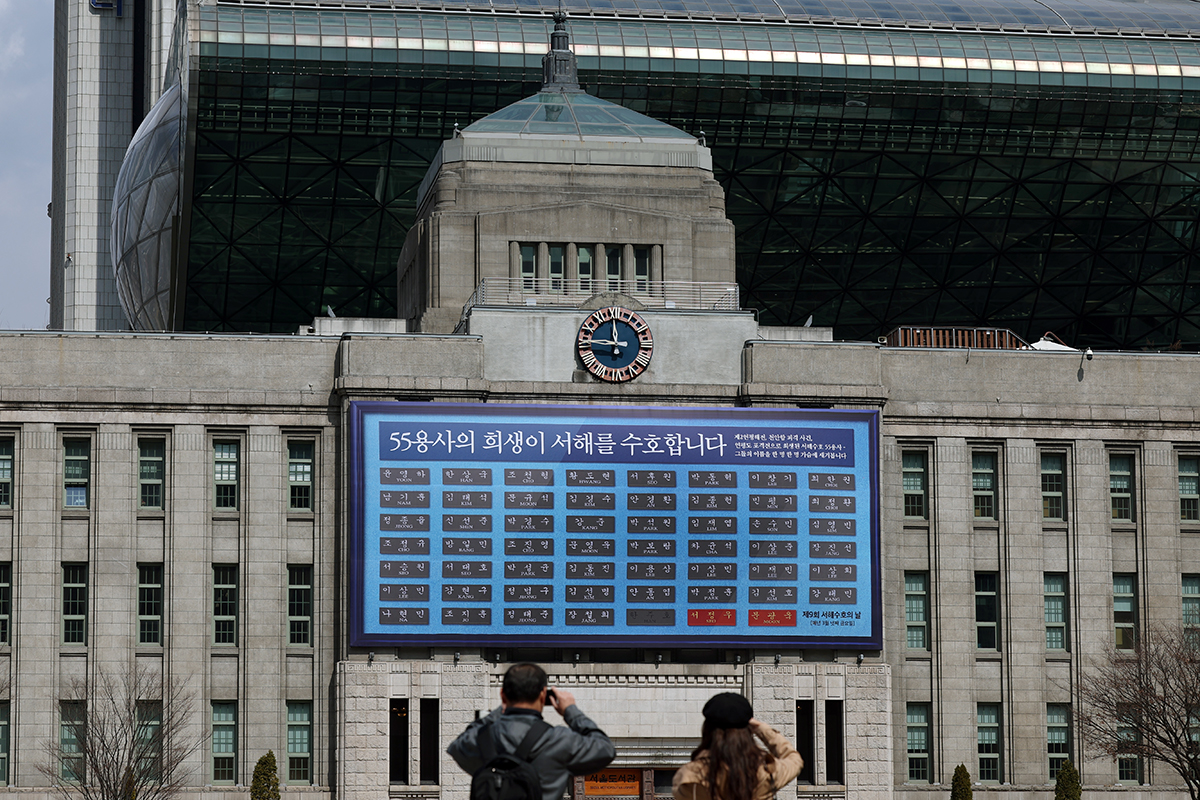 Am 20. März, zwei Tage vor dem 9. Tag der Verteidigung des westlichen Meeres, machen zwei Bürger Fotos von Namen der 55 gefallenen Soldaten auf der riesigen Tafel an der Wand der Seoul-Bibliothek. 