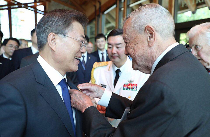  Präsident Moon Jae-in (links) erhält am 28. Juni während 
 seines Besuches des Nationalmuseums des Marine Corps am Rande von Quantico, im 
 Bundesstaat Virginia, ein Abzeichen der US-Marine-Corps vom ehemaligen 
 Generalleutnant Stephen Olmstead, einem Kriegsveteran der Schlacht um den Changjin-Stausee (장진호 전투, 1950), überreicht. Präsident Moon schrieb 
 auf seiner Facebook Page, dass Generalleutnant Olmstead „ein lebender Beweis 
 der Geschichte“ sei. 