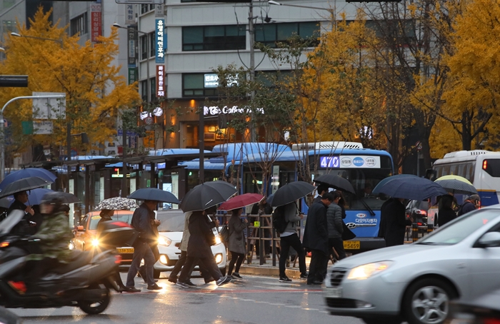 Menschen mit Regenschirmen an der Kreuzung Sejong-ro in Seoul gehen am 8. November im Regen zur Arbeit. ⓒ Yonhap News