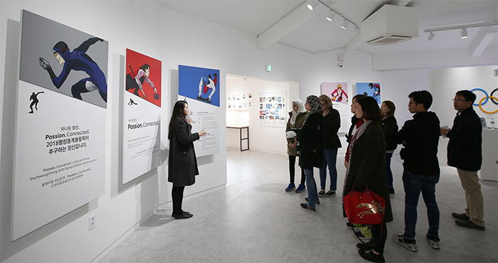 A group of tourists listen to an explanation about construction progress and preparation for the Winter Games at the 2018 PyeongChang House.