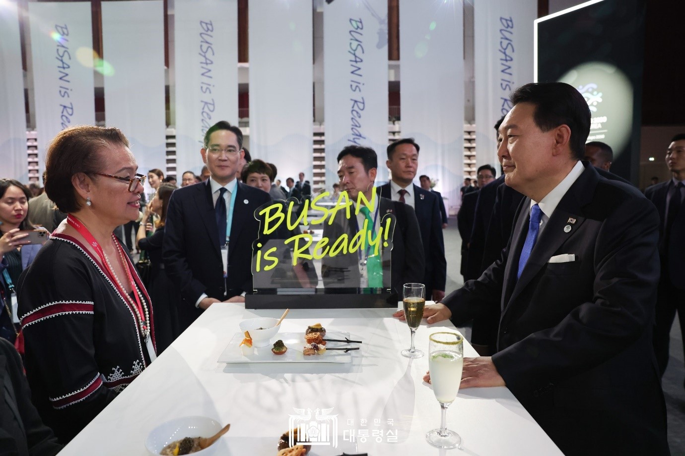 Präsident Yoon (rechts) grüßte am 21. Juni mit Teilnehmenden vom „offiziellen Empfang für die 2030 Busan World Expo“ in einem Sportzentrum in Issy-les-Moulineaux von Paris. Dabei wurden „die Gedenkbriefmarke von BTS“, dem PR-Botschafter für die 2030 Busan World Expo, und Schlüsselanhänger „BUSAN IS READY“, an deren Herstellung Kim teilnahm, übermittelt.