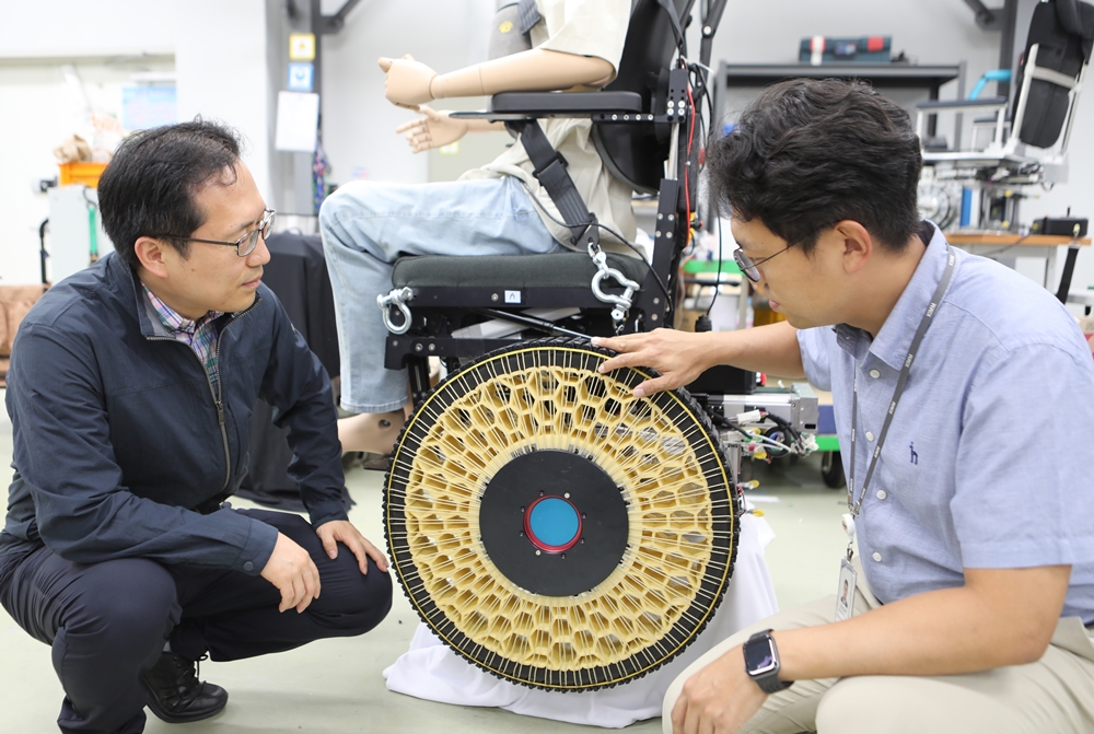 Seonghyeok Song, leitender Forscher vom Institute of AI Robotics (rechts), und Institutsleiter Dongil Park beobachten einen Rollstuhl mit Morphing-Rädern.