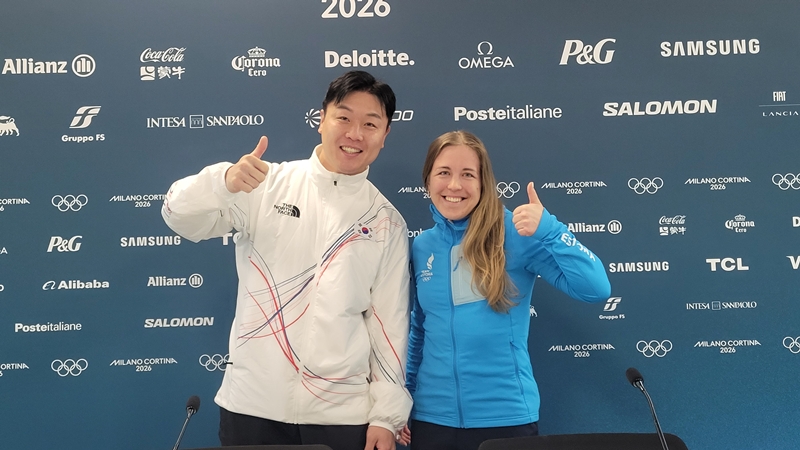 Der koreanische Bobsportler Won Yun-jong (links) und Johanna Talihärm, die estnische Biathletin, posieren am 19. Februar im Athletendorf der Olympischen Winterspiele 2026 in Mailand und Cortina d’Ampezzo für ein Erinnerungsfoto, nachdem sie als Athletenvertreter des IOC-Athletenkomitees ausgewählt wurde 