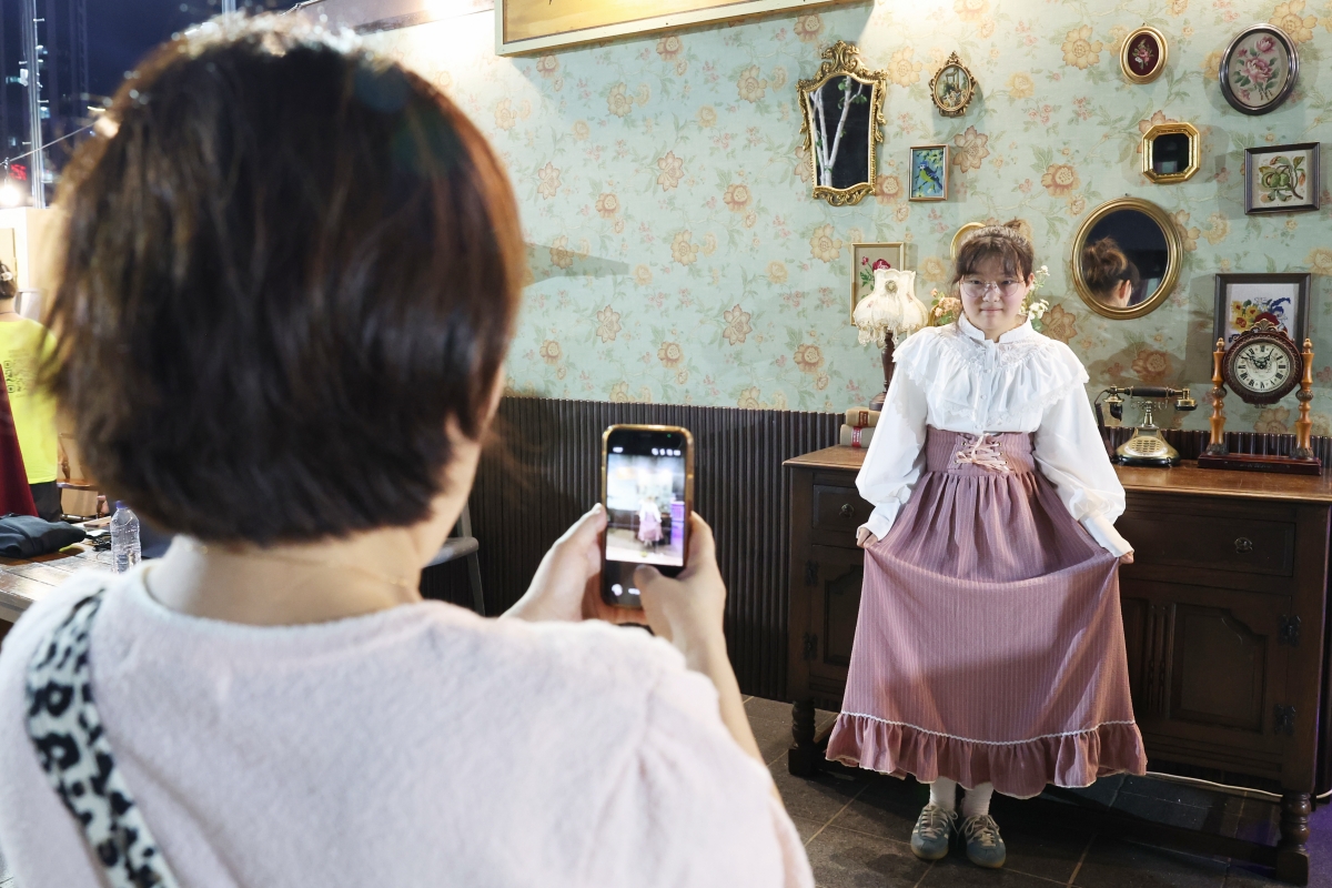 Am 25. Juli posiert eine Besucherin in Kleidung im Stil der 1950er Jahre auf dem Yurari-Platz in Jung-gu in Busan bei der Veranstaltung „2026 Busan Wartime Capital Heritage Night“ für ein Erinnerungsfoto