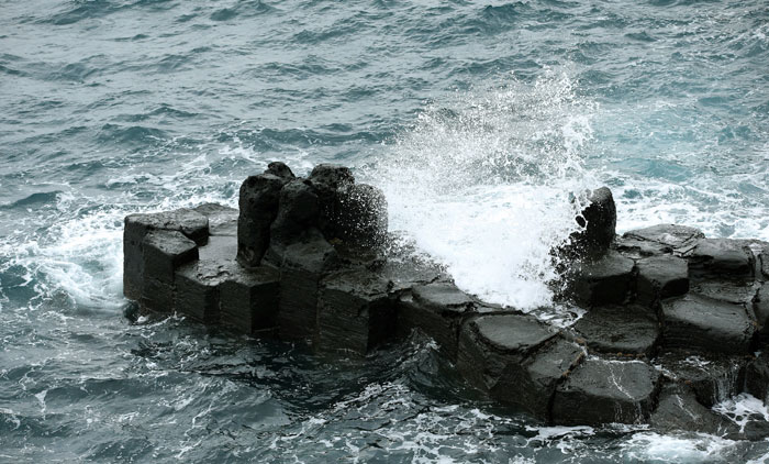 제주도 중문관광단지 해안에 있는 주상절리대. 육각형 기둥이 겹겹이 층을 이루고 있다. 현무암질 용암류가 급격히 식으며 발생하는 수축작용으로 만들어졌다.