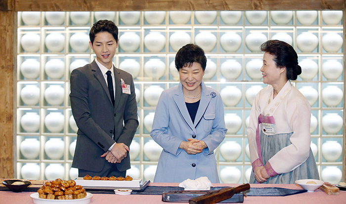Präsidentin Park Geun-hye (Mitte) spricht am 11. April mit Yoon Sook-ja (rechts), Direktorin des Institute of Traditional Korean Food, während der Eröffnungszeremonie für die „K-Style Hub“ (,Zentrum für den koreanischen Stil‘). Davor bereitete Präsidentin Park Yakgwa zu, ein traditionelles koreanisches Dessert aus Mehl und Honig. Assistiert wurde ihr dabei von Schauspieler Song Joong-ki (links).