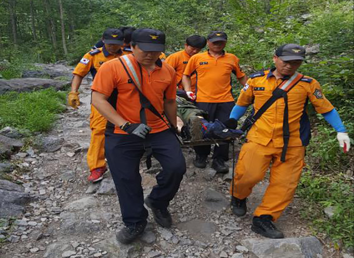 The Ministry of the Interior will begin test runs of four new IT-based public services starting this year. One of them is a new nationwide search and rescue service that sends GPS coordinates of a missing person on the mountainside to rescue workers. The photo shows rescue workers from the Miryang Fire Station as they help an injured hiker down from the mountainside.