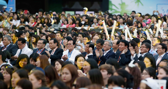 외국인, 내국인 관람객들과 함께 K-POP 그룹의 공연을 보고 있다.