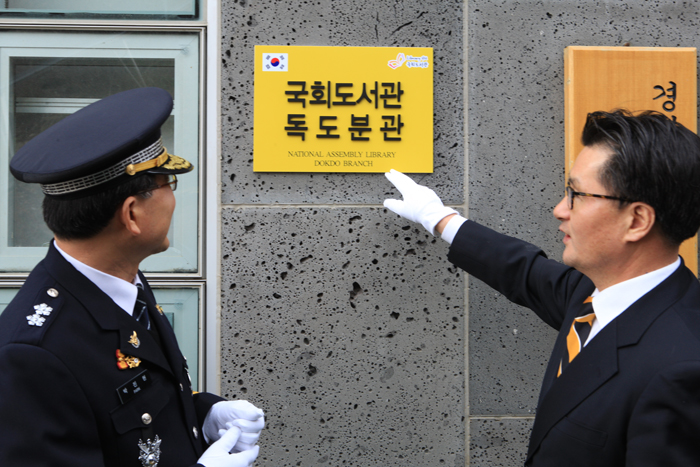 Gwanak District Mayor Yoo Jong-pil (right) shakes hands with a police officer in celebration of the National Assembly Library's Dokdo branch. 