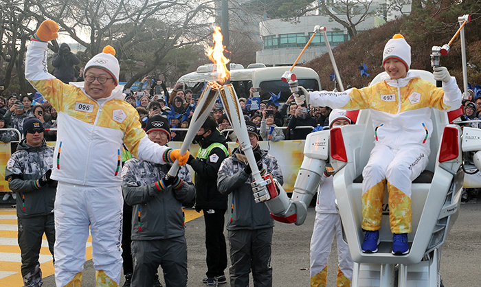 오준호 한국과학기술원(KAIST) 교수(왼쪽)가 11일 대전시에서 탑승형 로봇 ‘FX-2’의 조종을 맡은 주니어 소프트웨어 창작대회 우승팀 대표 이정재 군에게 성화를 전달하고 있다.
