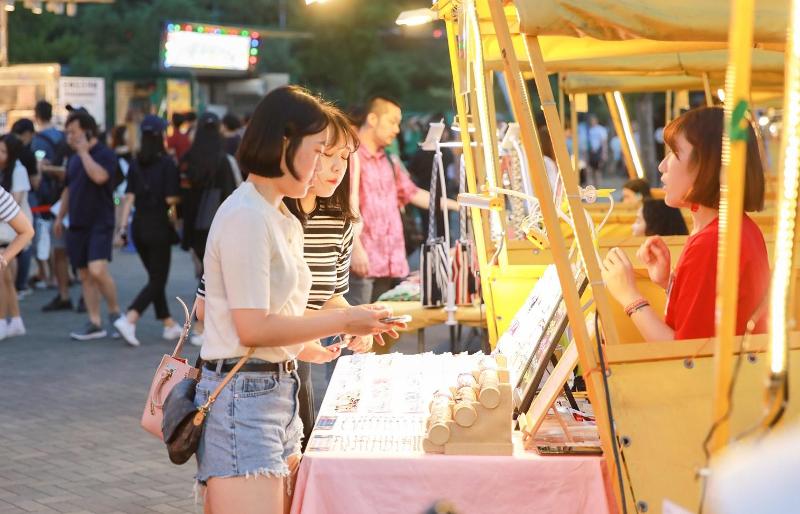Die Leute auf dem Hangang Mondscheinmarkt 2019 schauen an den vielen Ständen der Veranstaltung vorbei.