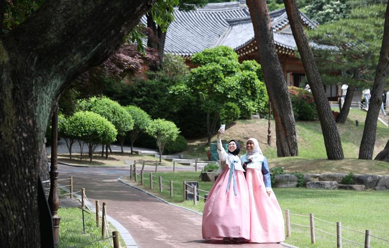 Ausländische Touristen im Hanbok schlendern am 24. Mai beim Hanbok-Erlebnis-Programm durch das Blaue Haus und machen ein Erinnerungsfoto.