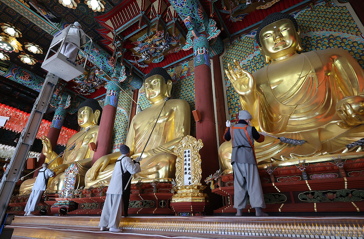 Am 18. Dezember wischen die Mönche in der Haupthalle Daewoongjeon im Jogyesa-Tempel den Staub auf der Buddhastatue.