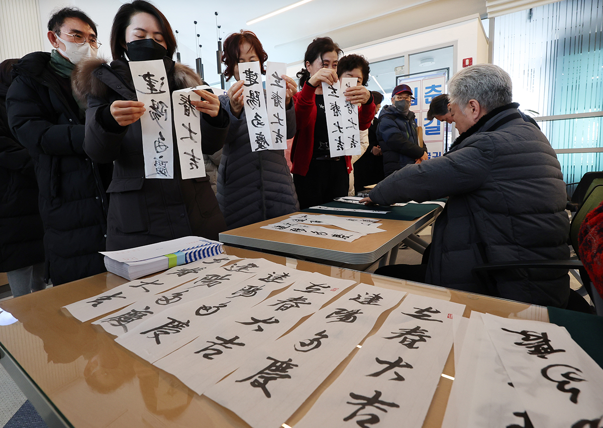 Am 16. Januar verteilt ein Kalligraph bei einer Veranstaltung im Kulturzentrum Daedonggol in Nam-gu, Busan, die kalligraphischen Passagen den Besuchern.