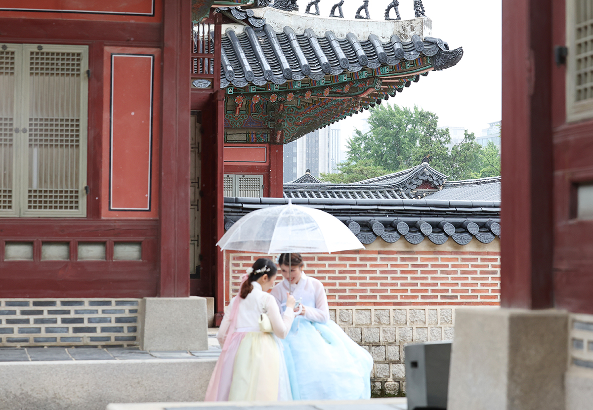 Am 20. Juni besuchen ausländische  Touristen im Hanbok mit den Regenschirmen den Gyeongbokgung-Palast in Jongno-gu, Seoul. An diesem Tag wurde vorhergesagt, dass es wegen der Regenzeit im ganzen Land viel regnet.