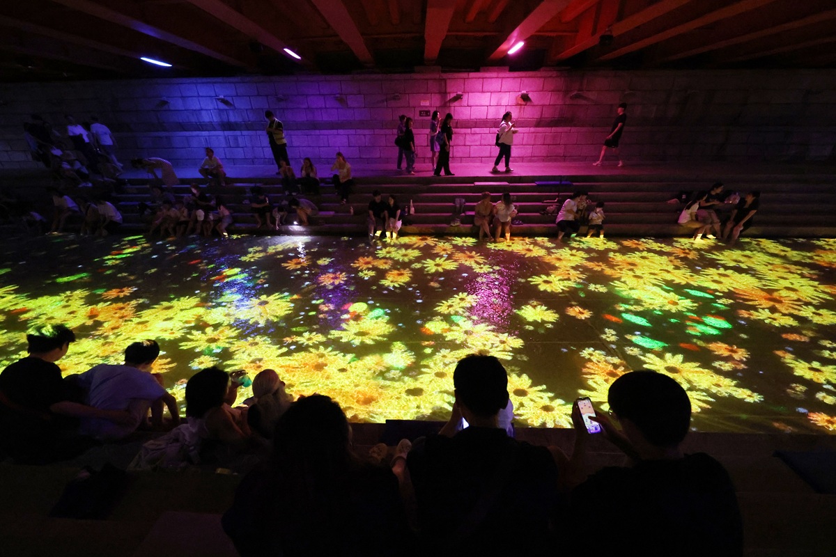 Am 31. Juli schauen sich Bürger am Fluss Cheonggyecheon in Jongno-gu, Seoul, das Medienkunstwerk 