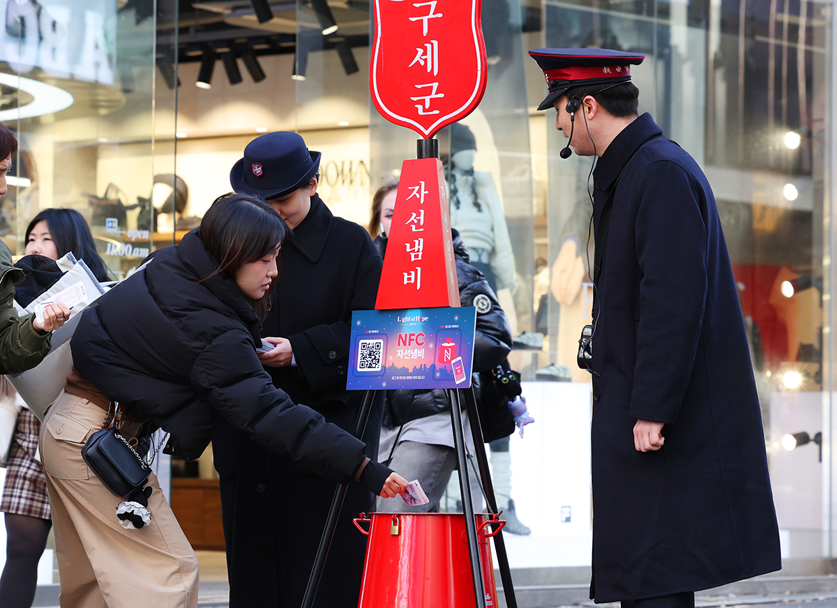 Am 28. November wirft eine koreanische Bürgerin Geld in den roten Spendentopf der Heilsarmee in der Myeongdong-Straße in Jung-gu, Seoul.