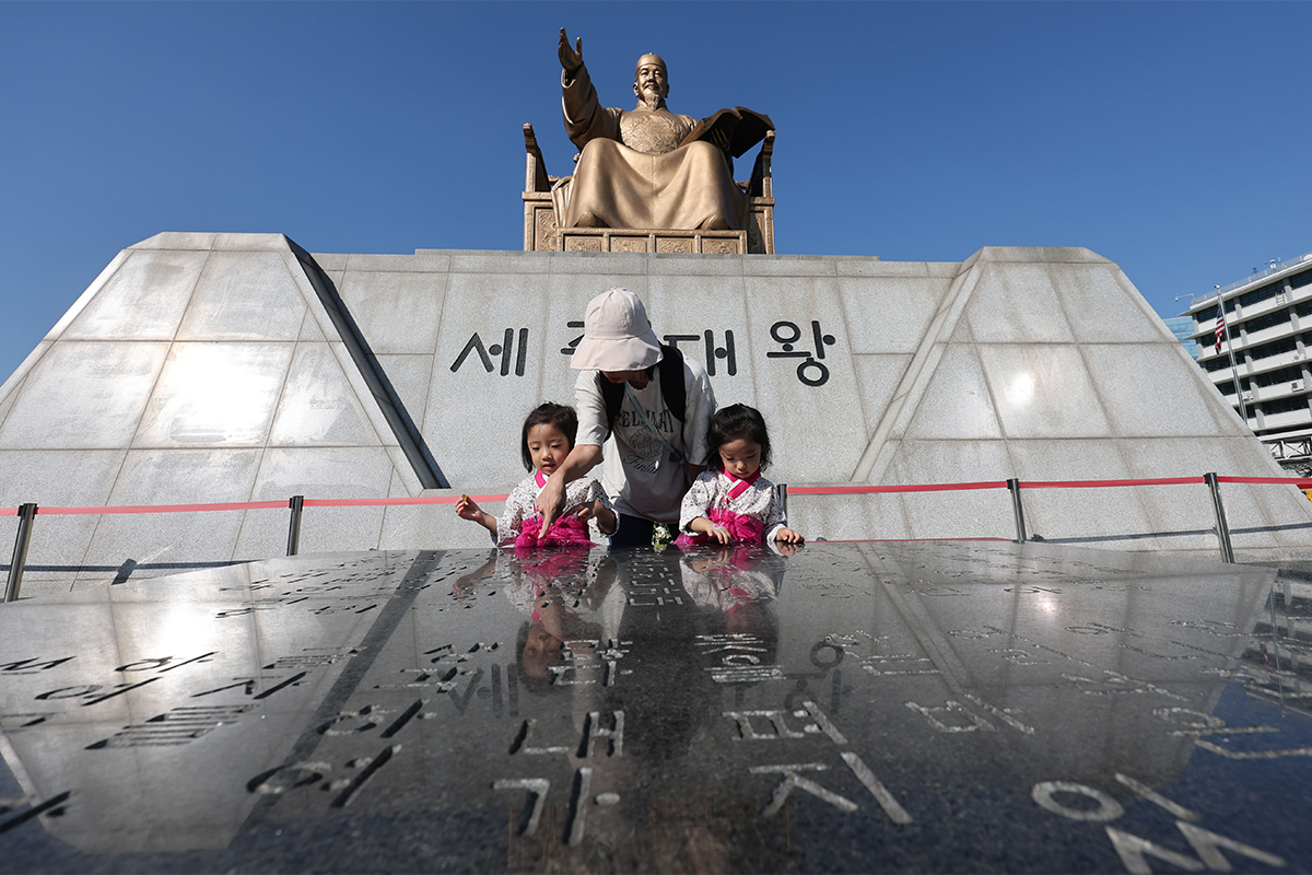 Am 8. Oktober, einen Tag vor dem 100. Jahrestag der Einf&uuml;hrung des Hangeul-Tages, betrachtet eine Familie vor der Statue von K&ouml;nig Sejong auf dem Gwanghwamun-Platz in Seoul eine Steintafel, in die die Pr&auml;ambel des Hunminjeongeum eingraviert ist.